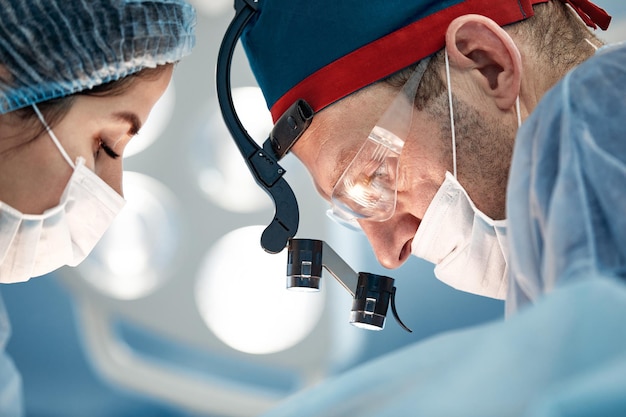 Photo surgeons are operating, a team of male and female doctors during the operation, doctors are strapped in the operating room.