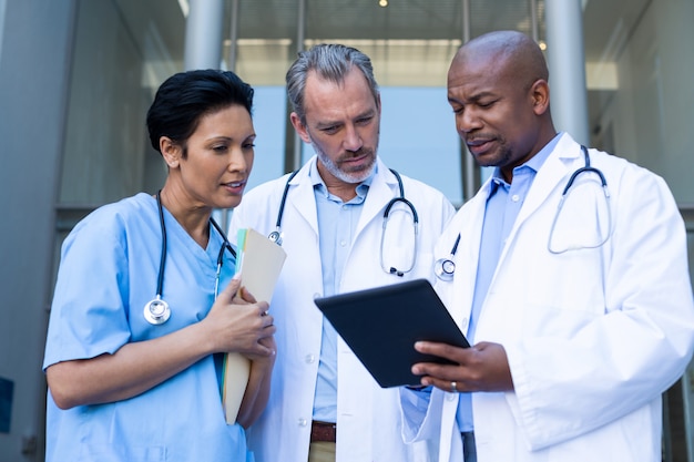 Surgeons and nurse having discussion on digital tablet