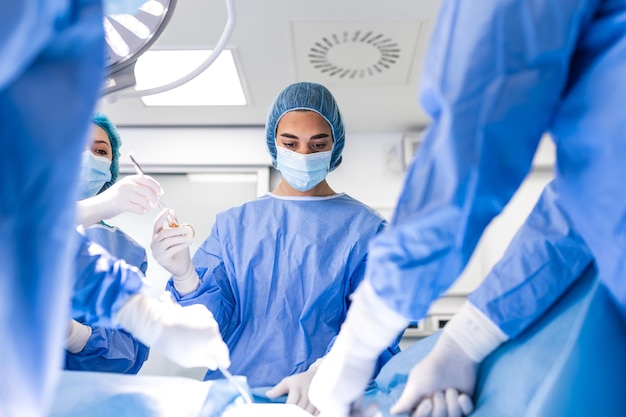 Surgeons operating below lighting equipment Male and female doctors are wearing blue scrubs They are working in hospital