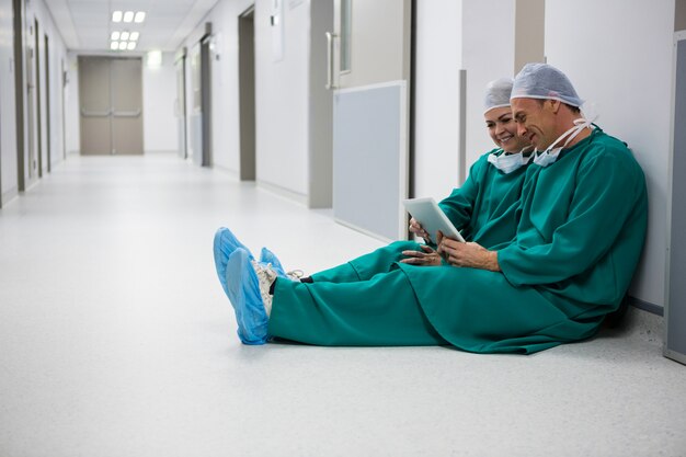 Surgeons using digital tablet in corridor