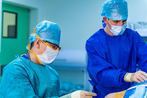 Surgeons working in operating room hospital background two male\
doctors at work circular background of an operation on a spinal\
cord vertebra