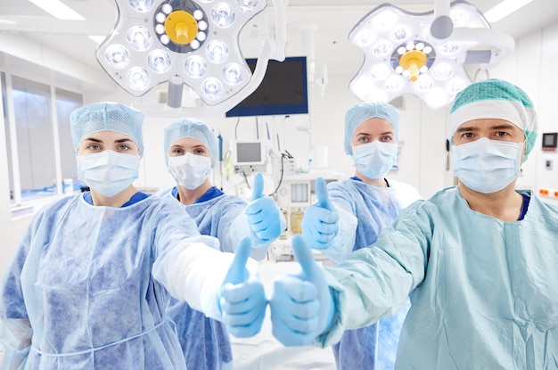 수술, 의학 및 사람 개념 - 엄지손가락을 치켜드는 병원 수술실의 외과의사 그룹
