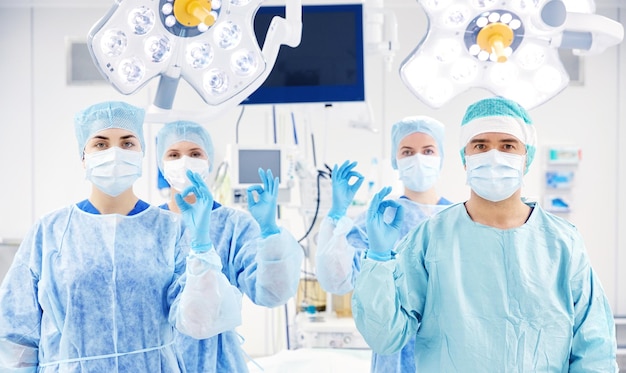 surgery, medicine and people concept - group of surgeons in operating, room at hospital