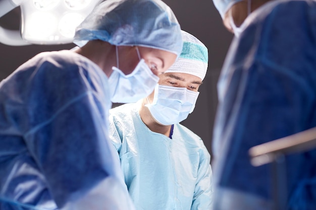 surgery, medicine and people concept - group of surgeons at operation in operating room at hospital