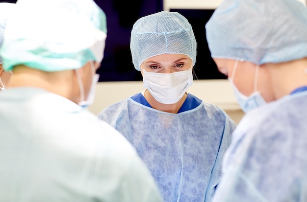 surgery, medicine and people concept - group of surgeons at operation in operating room at hospital