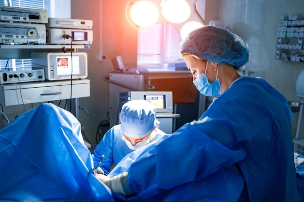 Surgery operation. Group of surgeons in operating room with surgery equipment. Medical background, selective focus