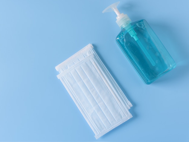 Photo surgical mask and  hand sanitizer  for washing on blue wall,top view
