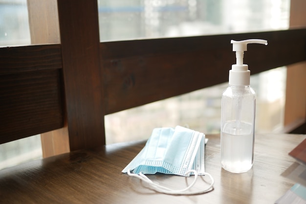 Surgical masks and hand sanitizer on table against a window