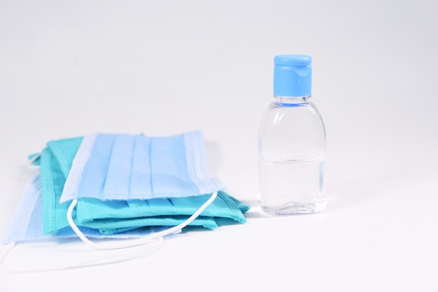 Surgical masks and hand sanitizer on white background .