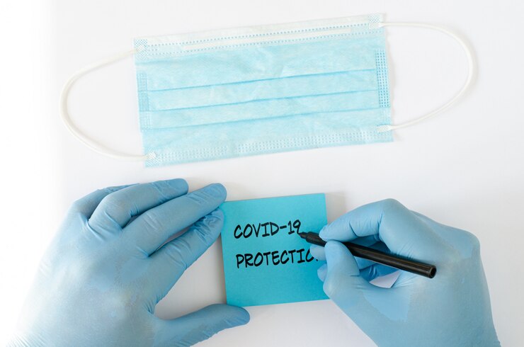 Photo 青い紙にcovid 19保護を記述した手袋を手にした手術用保護マスク