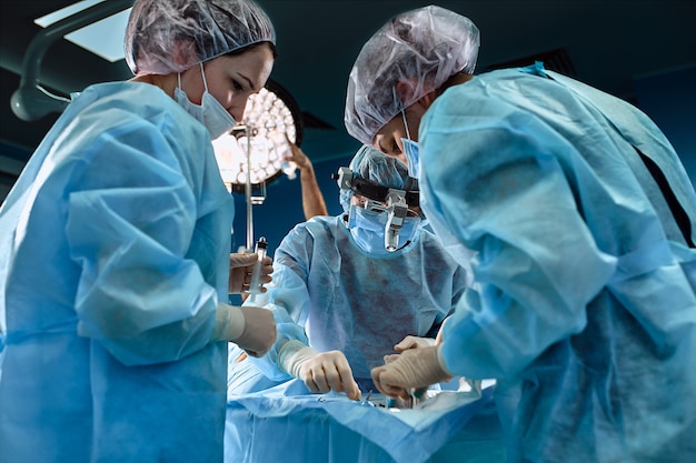 Foto equipe chirurgica in sala operatoria, primo piano un team internazionale di medici professionisti in una moderna sala operatoria si sta operando per salvare vite umane