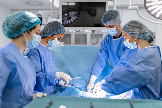 Surgical team performing surgery in modern operation theaterTeam of doctors concentrating on a patient during a surgeryTeam of doctors working together during a surgery in operating room