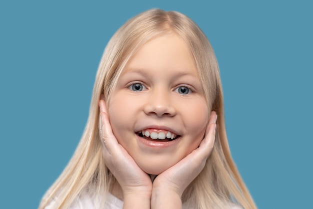 Surprise, delight. close up of cute face of joyful surprised\
girl with long blond hair and gray eyes