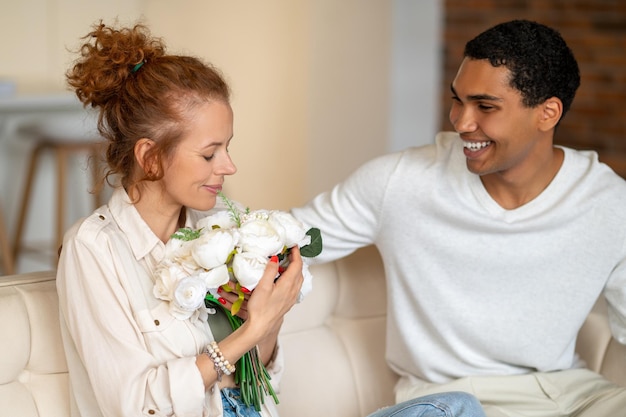 Photo surprise. man giving flowers to his woman and both looking happy