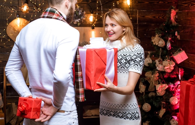 Surprise for sweetheart. Merry christmas and happy new year. Christmas gifts. Man handsome with gift box surprise for girlfriend. Man hipster give gift to girl christmas decorations background