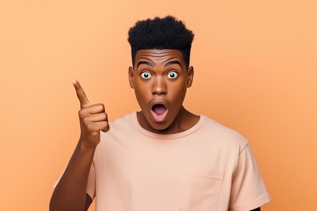 Surprised African teen guy holding laptop pointing at computer advertising wow offer Amazed ethnic teenager student boy using pc feeling shocked isolated on beige background