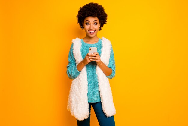 Surprised afro american girl use smartphone blog search social network news scream wow omg wear white fluffy blue pants trousers teal stylish trendy sweater isolated shine color wall