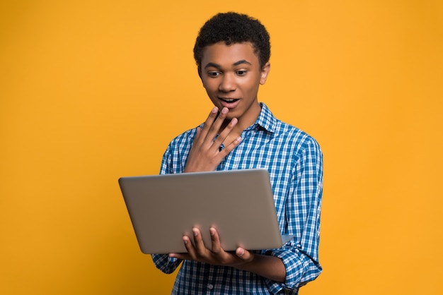 Surprised Afro American teen looks at laptop screen.