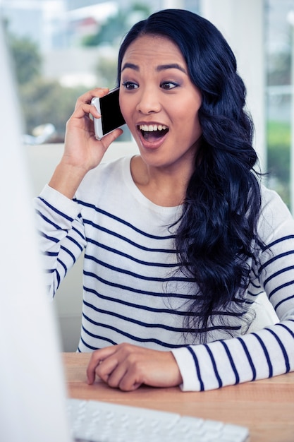 Surprised Asian woman on phone call in office