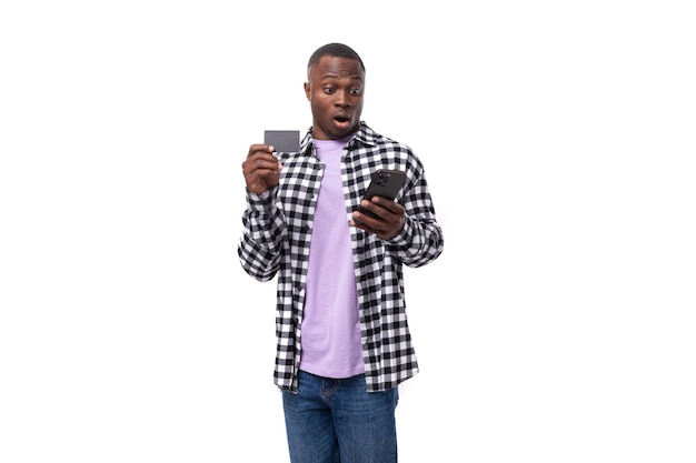 Surprised attractive year old african guy dressed in a plaid black and white shirt uses internet