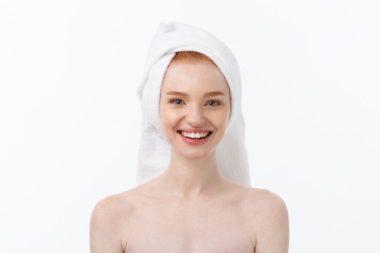 Photo surprised beautiful young woman after bath with a towel on her head isolated on white background. 