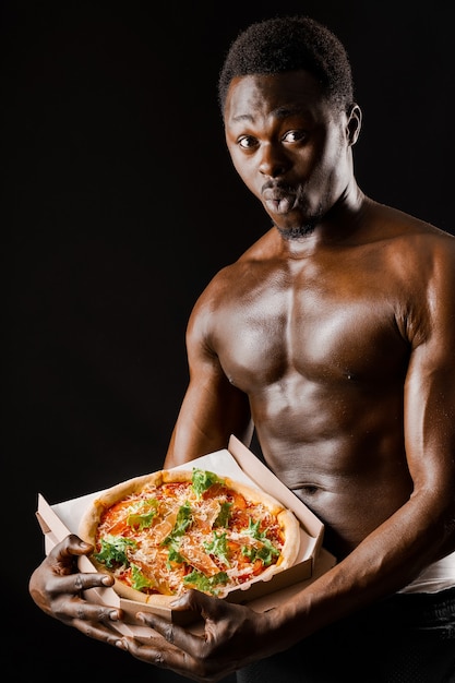 Surprised black fit man with pizza in hands