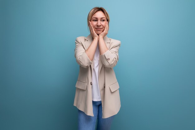 Surprised blond young business woman in jacket on studio background