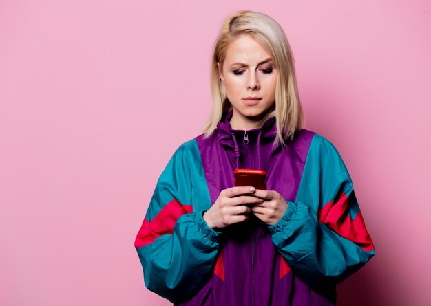 Surprised blonde woman in sport suit of 90s on pink wall