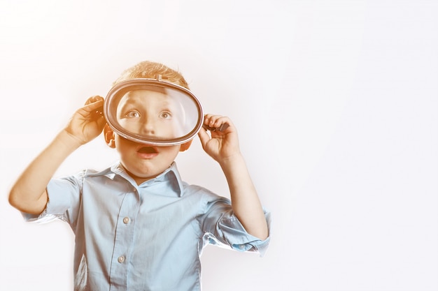 A surprised boy in a blue shirt wearing an underwater mask for swimming  