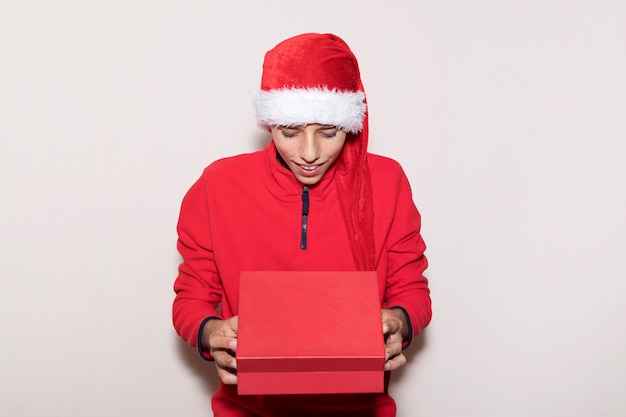 A surprised boy in Santa hat opens gift box