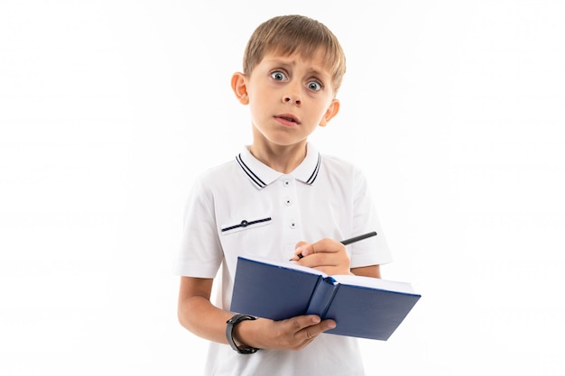 Surprised boy with a book and pen on white