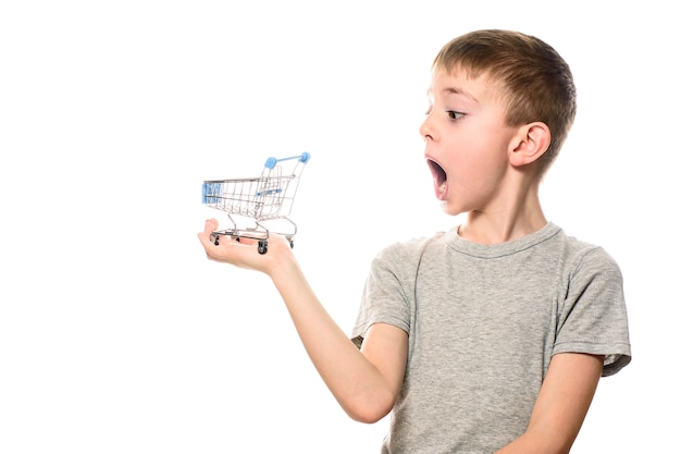 Surprised boy with open mouth holding a small metal shopping cart on a palm.