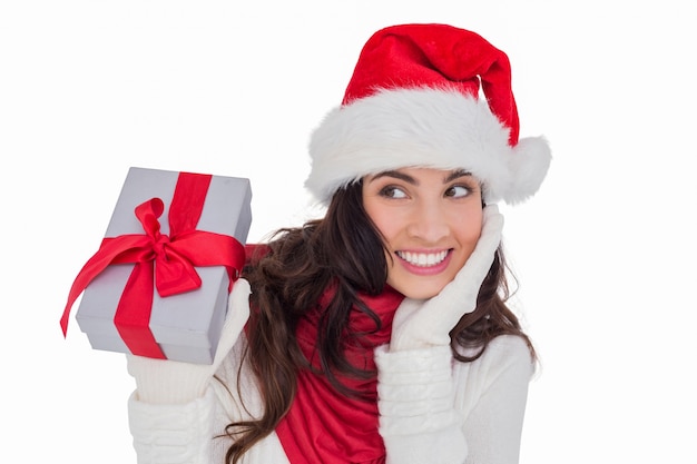 Surprised brunette in santa hat holding gift