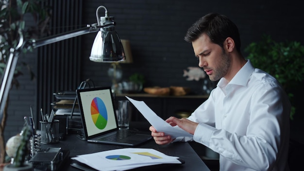 Surprised businessman analyzing business documents at remote workplace