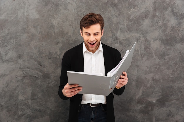 Surprised businessman standing over grey wall