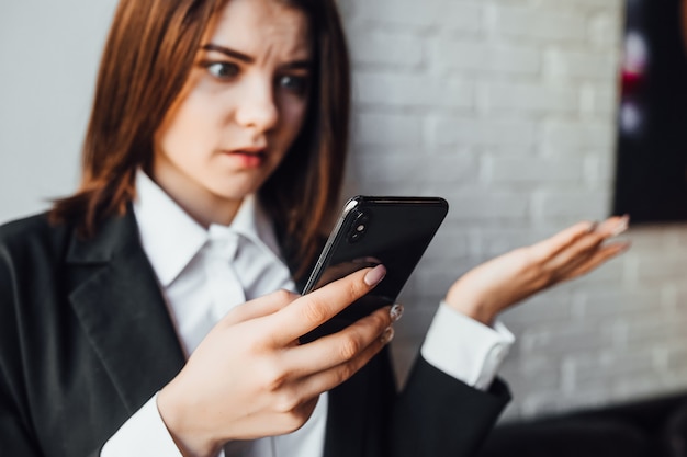 Surprised businesswoman reading news in phone