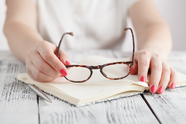 Surprised businesswoman taking off glasses while reading in office