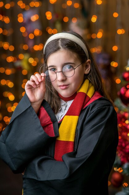 Photo surprised caucasian little girl in witch cosplay reads magic book while holding magic wand