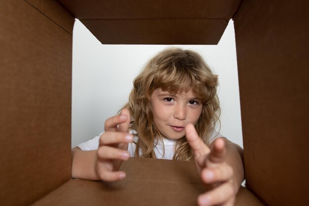 Foto il bambino sorpreso età anno disimballando aprendo la scatola di cartone e guardando all'interno del pacco consegna su