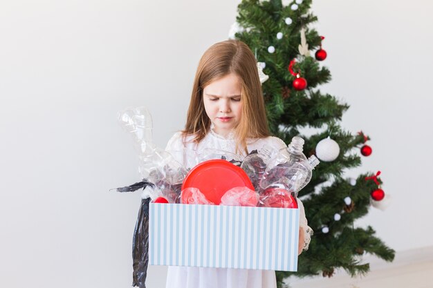 Surprised child carrier box with plastic trash over christmas tree