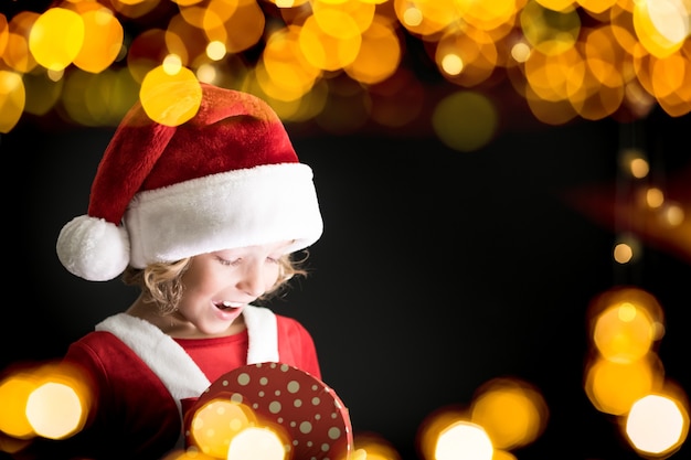 Surprised child holding Christmas gift box. happy kid having fun at home. Xmas holiday concept