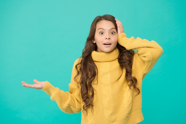 놀란 아이 삶에 대한 긍정적인 태도 어린이 심리학 놀란 느낌 사랑스러운 놀란 소녀는 노란색 스웨터를 입고 청록색 배경 서프라이즈 컨셉 좋은 분위기 감성적인 아기