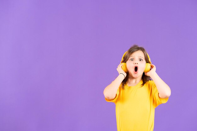 Surprised child wearing headphones isolated on purple background