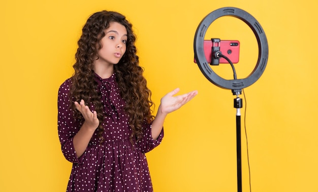 Surprised child with curly hair making video for blog