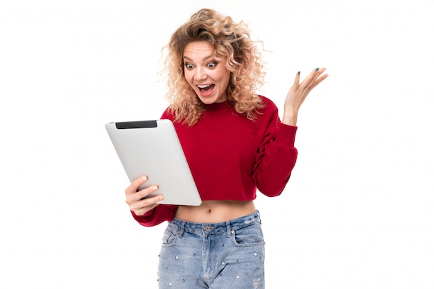 Surprised curly blonde with on tablet on white