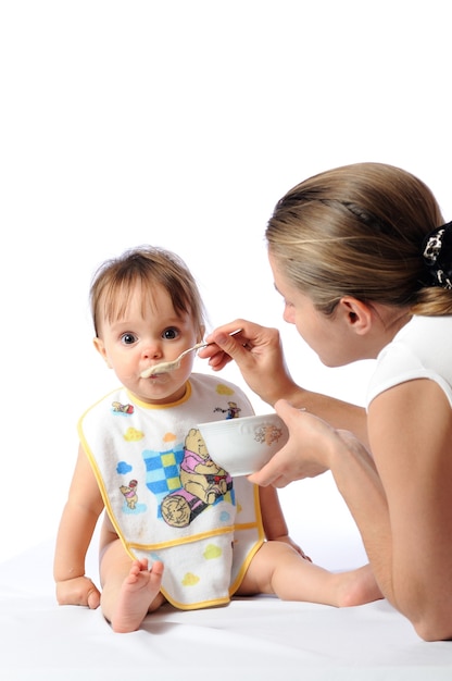 Piccola neonata sveglia sorpresa che mangia alimento dal cucchiaio