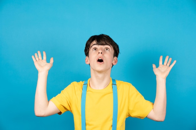 Surprised cute teenager looking up isolated on blue background