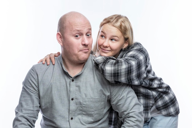 A surprised dad in a gray shirt and a smiling adult teenage daughter in a checkered shirt are hugging Love and tenderness Isolated on a white background