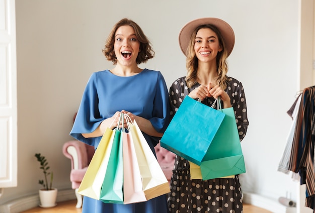 Photo surprised excited young women shopaholics