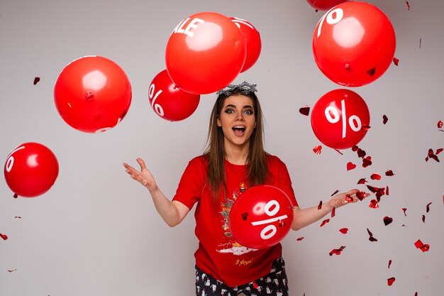 Surprised female in t-shirt and comfortable pants throws up a lot of air balloons